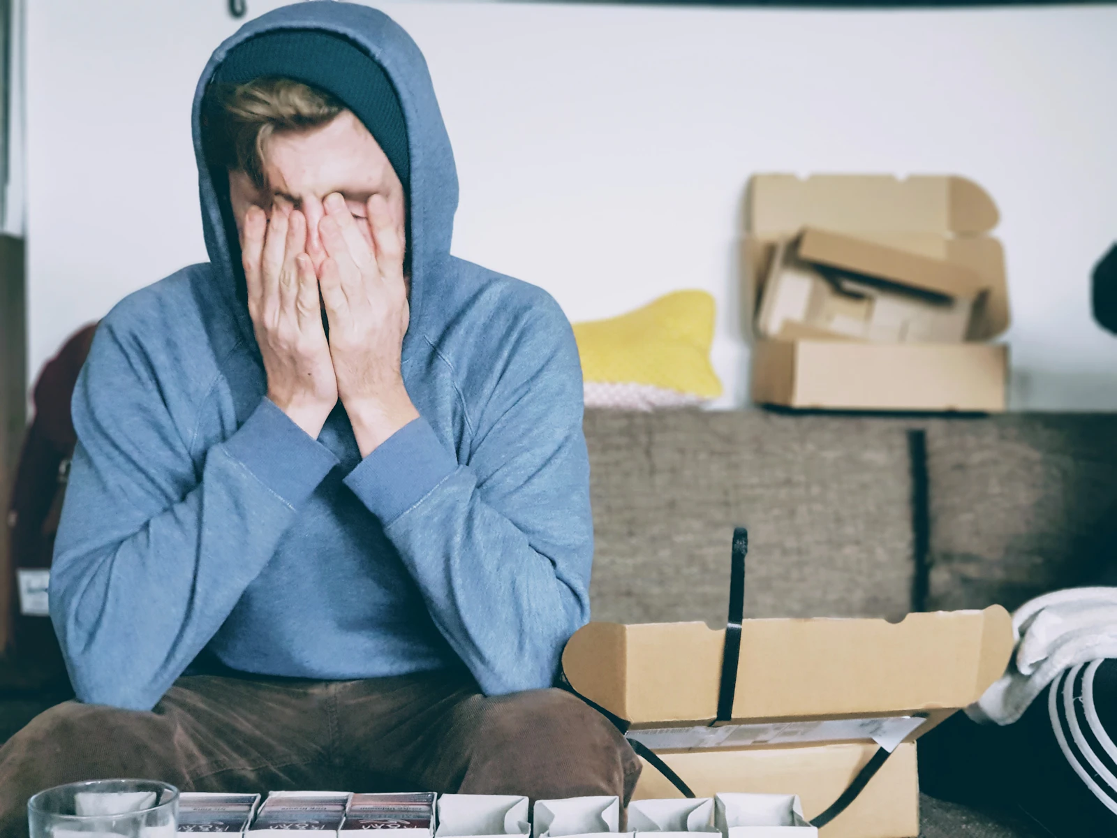 Overwhelmed homeowner sitting among moving boxes, waiting for junk removal
